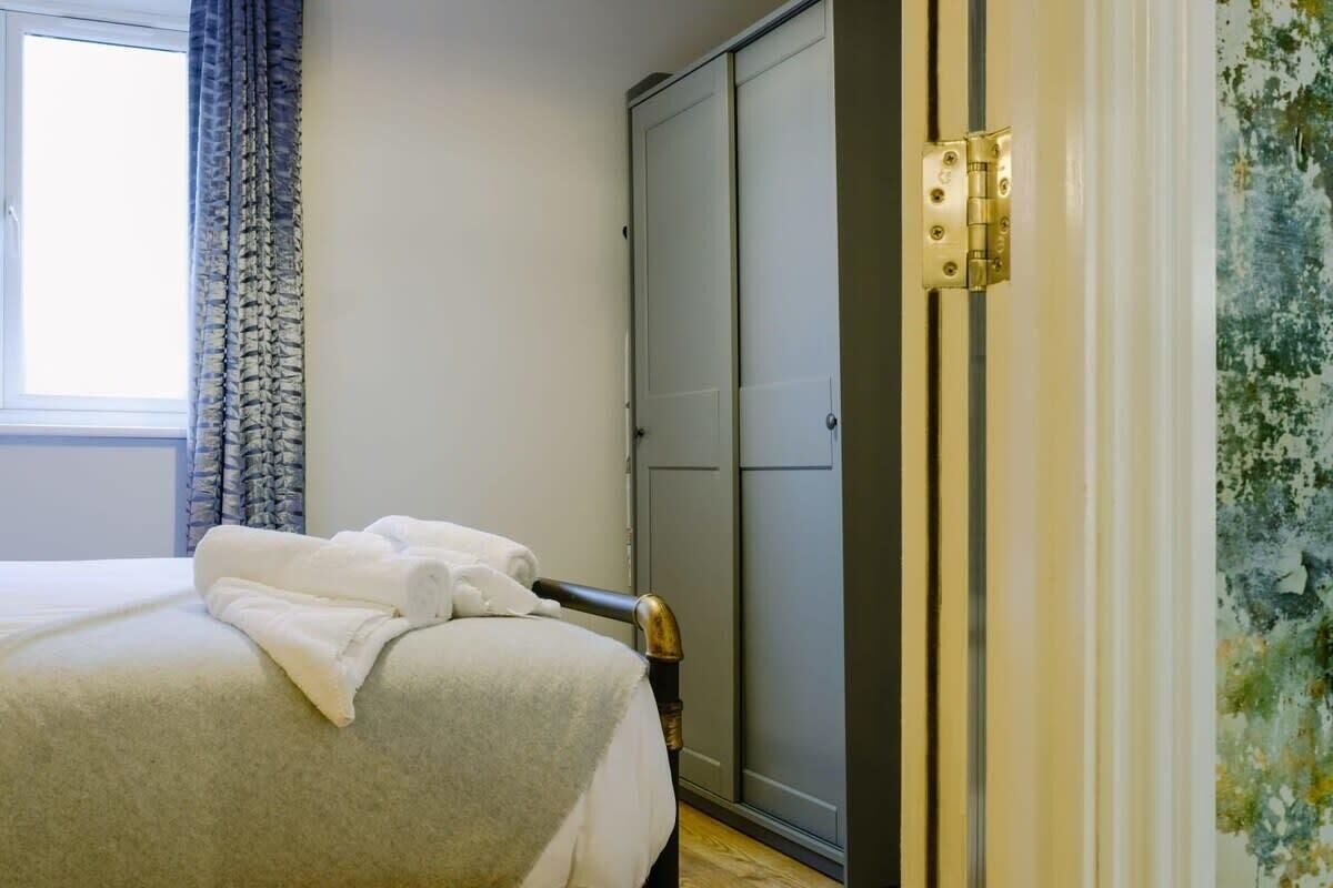 Una camera da letto con un letto, un armadio e una finestra con tende.