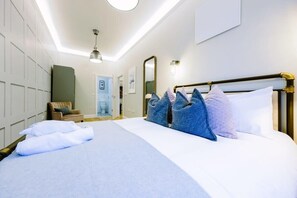 A hotel room with a large bed, a wooden headboard, and a seating area with a chair and a small table. - One Bedroom Apartment Close to Cribbs Causeway! (Bristol)