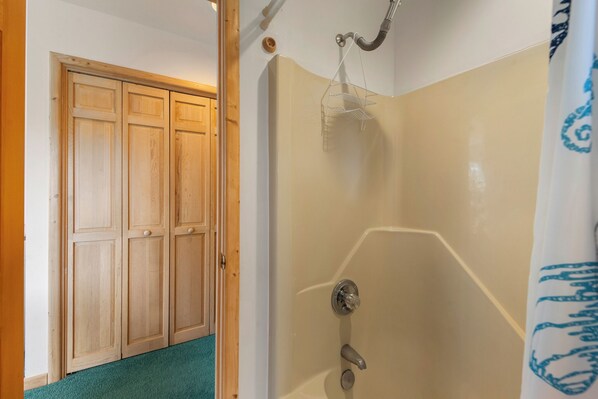 Een badkamer met een douche, een houten garderobe en een handdoekrek.