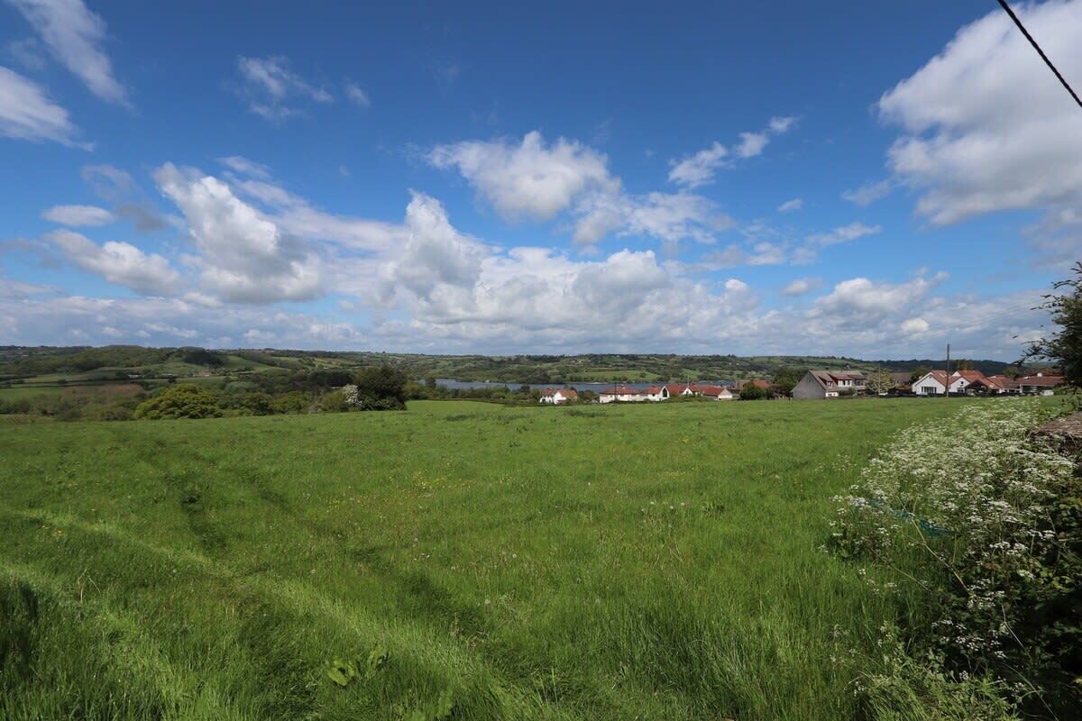 Paesaggio rurale con un campo, case e cielo sereno.