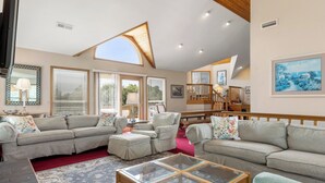 Un soggiorno spazioso con soffitto alto, ampie finestre e un'accogliente zona relax.