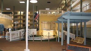 A hotel atrium with a central garden, a flag, a wooden bench, and a covered seating area. - Gorgeous 2 Bedroom Condo - Pool/Tiki Bar/Beach (Hilton Head Island)