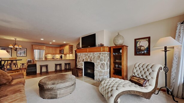 A living room with a stone fireplace, a large armchair, and a sofa. - Boutique Complex Steps Away from Mammoth! Hike, Mountain Bike, Free WiFi and Free Parking! by RedAwning (Mammoth Lakes)