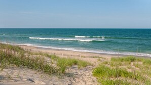 Una playa con dunas de arena y una valla de madera.