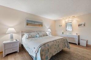 A bedroom with a bed, nightstands, a dresser, a mirror, and a painting on the wall.