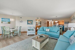A living room with a blue sofa, a coffee table, and a dining area with a table and chairs.