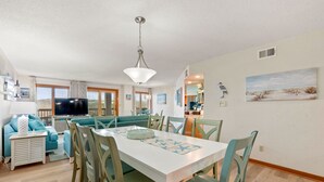 Een moderne woonkamer met een eethoek, een televisie en een keuken op de achtergrond.