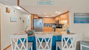Een keuken met houten kastjes, een granieten aanrechtblad en een bordje met de tekst 'BEACH HOUSE'.