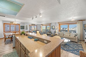 A spacious living area with a large island, a sofa, and a dining table.