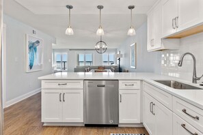 Enjoy cooking in this well-equipped kitchen with a dishwasher, sink, and ample lighting.