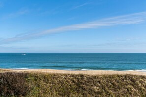 Enjoy the serene coastal landscape with a sandy beach and a small boat on the horizon.