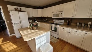Une cuisine avec des meubles blancs, un réfrigérateur, un four à micro-ondes, un four et un évier.
