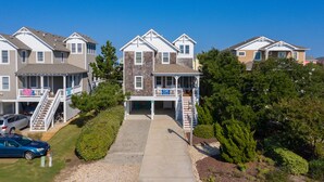 A row of townhouses with a central entrance, a covered porch, and a small outdoor seating area. - On Holiday: Oceanside, Private Pool, Spa (Nags Head)