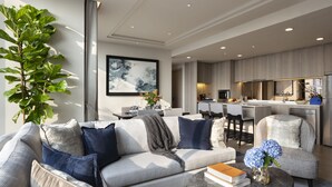 A modern living room with a sofa, armchairs, a coffee table, and a large plant.