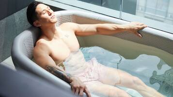 A person relaxing in a bathtub with a window in the background.