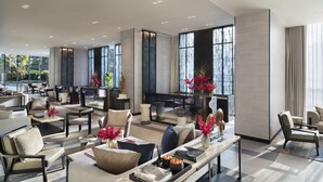 A spacious lobby with multiple seating areas, large windows, and modern decor.