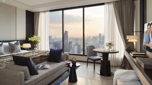 Een moderne hotelkamer met een weids stadsgezicht, een bank, een eettafel en een televisie.