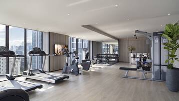 Un gimnasio amplio con cintas de correr, elípticas y equipo de pesas.