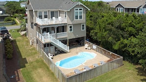 A two-story house with a backyard swimming pool, a deck, and a covered patio area. - Jockeys Ridge 385: Oceanside, Private Pool, Spa (Nags Head)