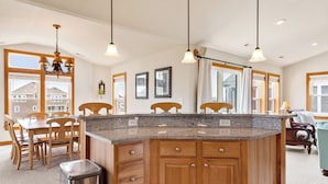 A modern kitchen with a granite countertop, wooden cabinets, and pendant lighting. - Jockeys Ridge 385: Oceanside, Private Pool, Spa (Nags Head)