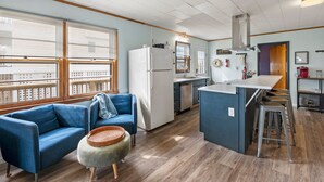 Une cuisine moderne équipée d’un réfrigérateur, d’une cuisinière et d’un coin bar. On y trouve un canapé bleu et un panier en osier.