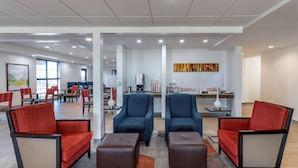 A modern hotel lobby with seating areas, a coffee station, and artwork on the walls.