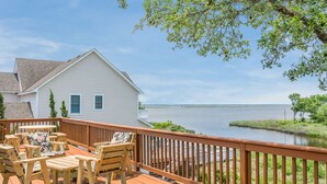 A wooden deck with outdoor furniture, a white house, and a view of a body of water. - Birdie: Private pool, Spa, Golf discounts (Corolla)