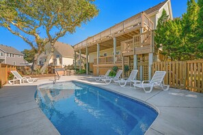 A swimming pool with lounge chairs and a wooden deck.