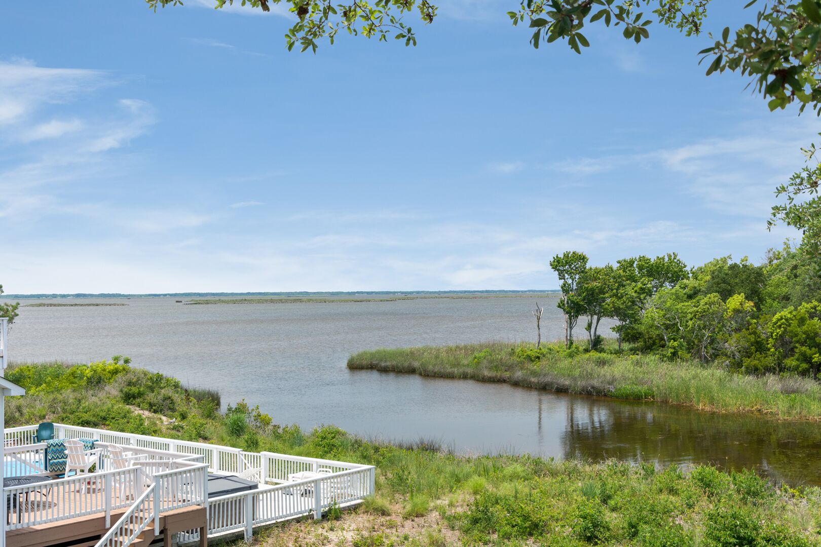 A waterfront property with a deck and outdoor seating area overlooking a calm body of water.