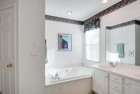 A bathroom with a bathtub, a large mirror, and a window with blinds. - Sounds Of Summer: Gated community, Soundside, Private Hot Tub, Club Amenities (Corolla)