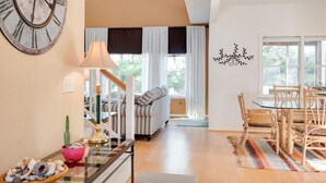 Un vaste espace de vie comprenant une grande horloge, une table à manger avec des chaises, un canapé et un escalier menant à un autre niveau.