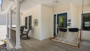 A porch with a swing chair and a hammock.