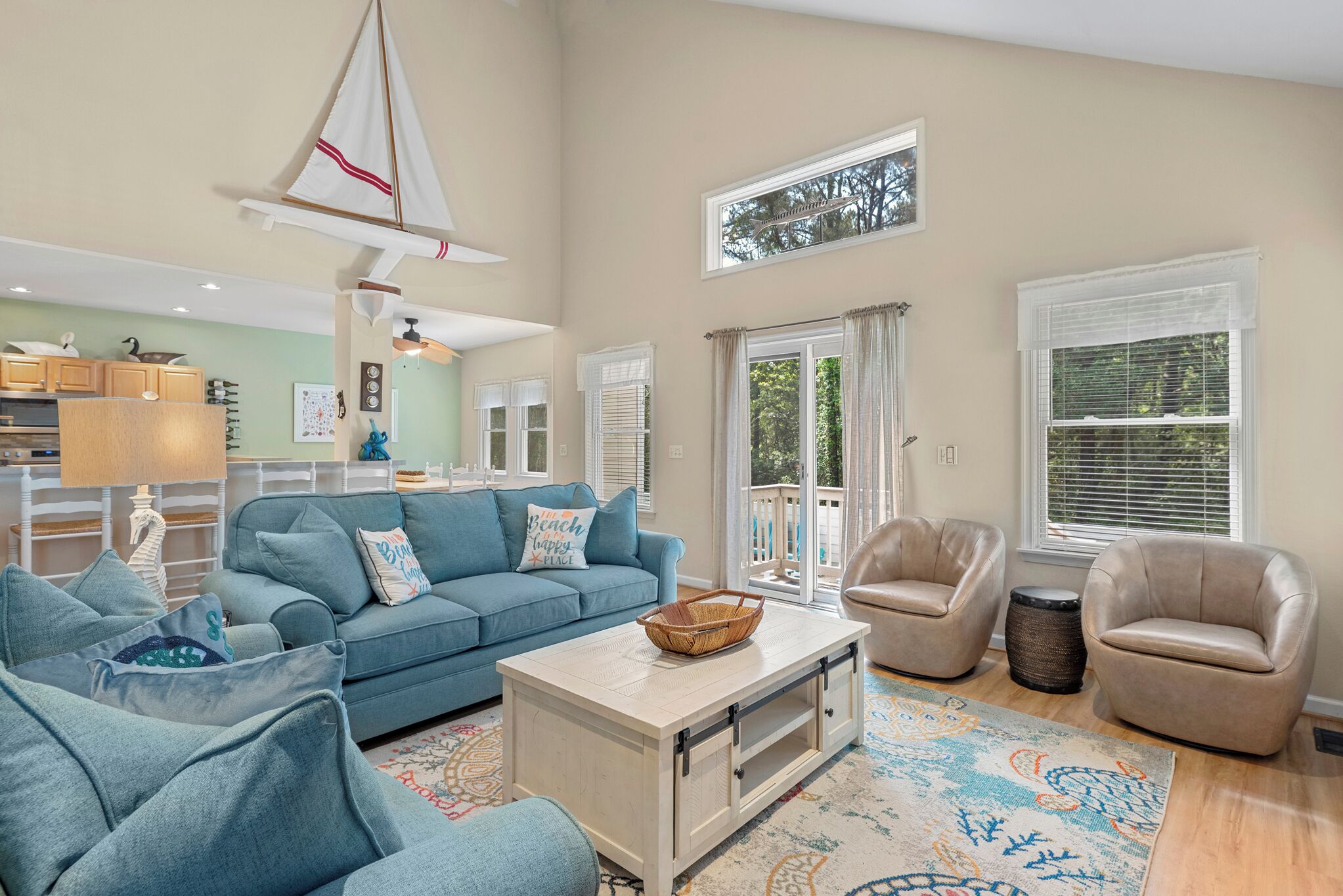 A spacious living room with a blue sofa, beige armchairs, and a coffee table.