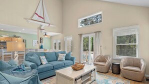 A spacious living room with a blue sofa, beige armchairs, and a coffee table.