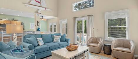 A spacious living room with a blue sofa, beige armchairs, and a coffee table.