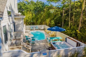 A backyard with a swimming pool, outdoor furniture, and a hot tub.