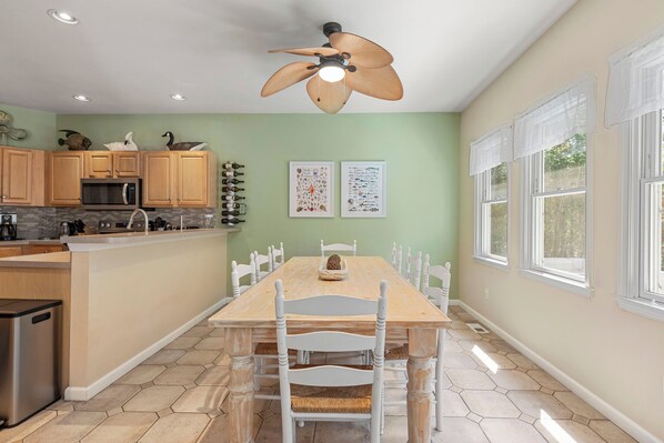 A kitchen with wooden cabinets, a microwave, and a dining table with chairs.
