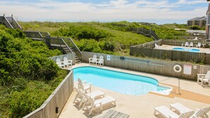 Zona de piscina amb gandules de fusta, una piscina petita i una tanca de fusta.