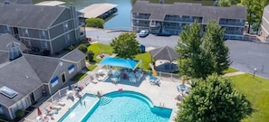 Luftaufnahme eines Wohngebiets mit Schwimmbad, Liegestühlen und einer überdachten Terrasse.