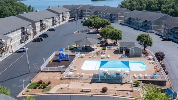 Zona residencial con piscina, sillas de descanso y parque infantil.