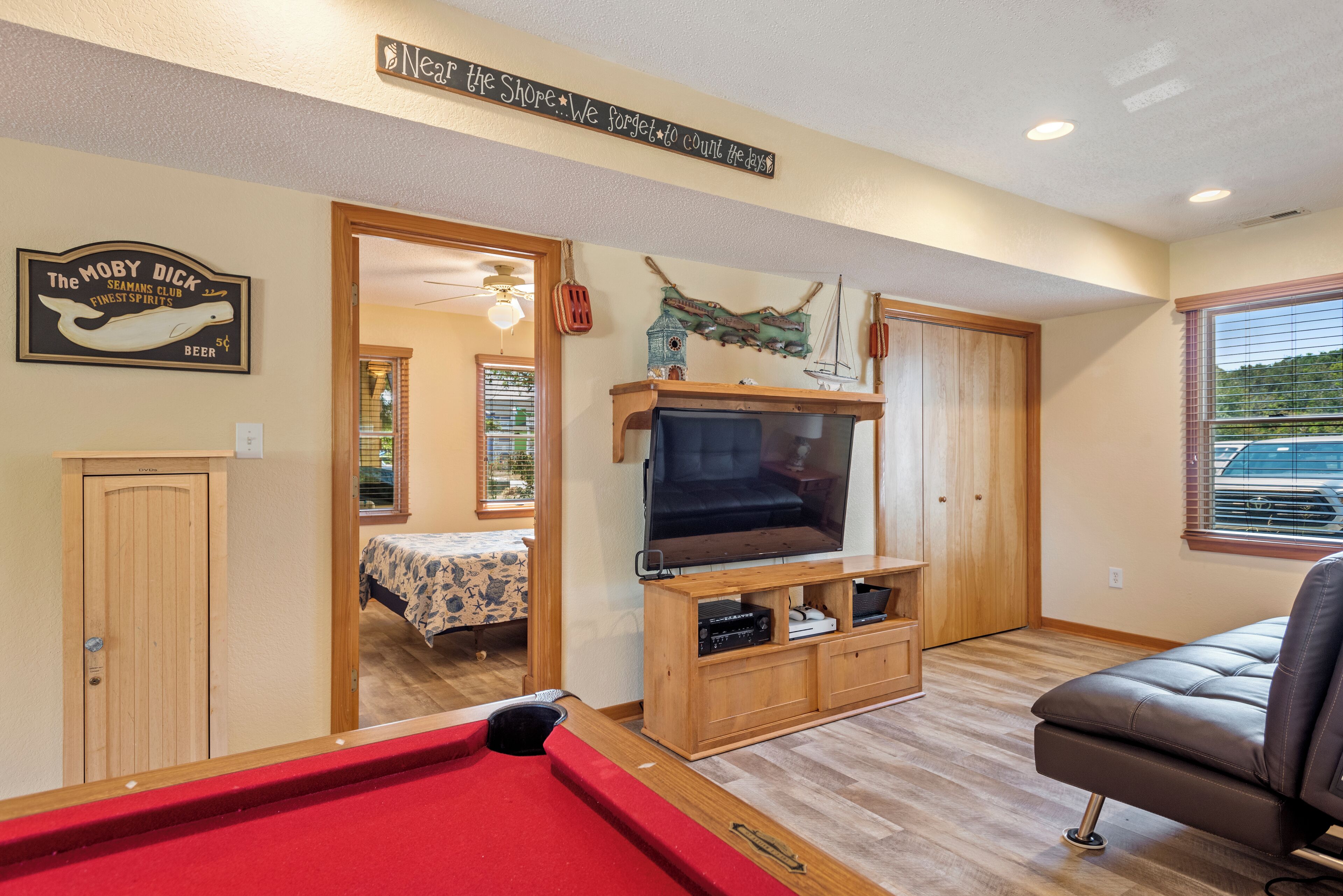 A cozy living room with a pool table, a television on a wooden stand, and a comfortable sofa.