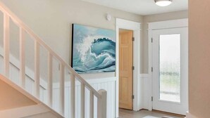A staircase with white railings leading to a room with a large painting of a wave on the wall, a wooden door, and a window. - Fish Tank: Oceanside, Private Pool, Hot Tub, close to beach & golf discounts! (Corolla)