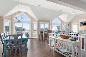 A spacious dining area with a high ceiling, large windows, and a view of the surrounding landscape.