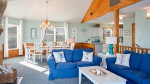 Een woonkamer met een blauwe bank, een witte salontafel en een houten plafondventilator.