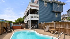 Une piscine avec une terrasse en bois, des chaises longues et un jacuzzi.