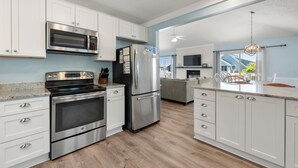 Une cuisine moderne avec des armoires blanches, des appareils en acier inoxydable et un plancher en bois.