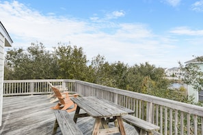 A wooden deck with benches and a table, overlooking a body of water and greenery.