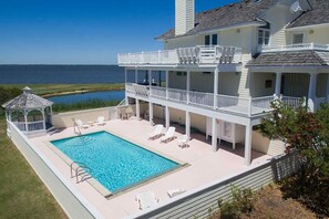 A two-story house with a large pool and a gazebo.