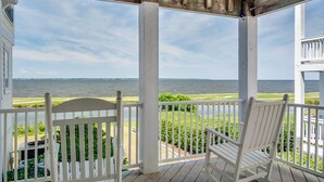 A wooden porch with white railings and rocking chairs overlooking a body of water. - Sunsets Forever: Soundfront, Private Pool, Hot Tub (Nags Head)