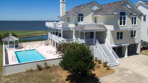 A large two-story house with a swimming pool, a covered patio, and a view of the water. - Sunsets Forever: Soundfront, Private Pool, Hot Tub (Nags Head)